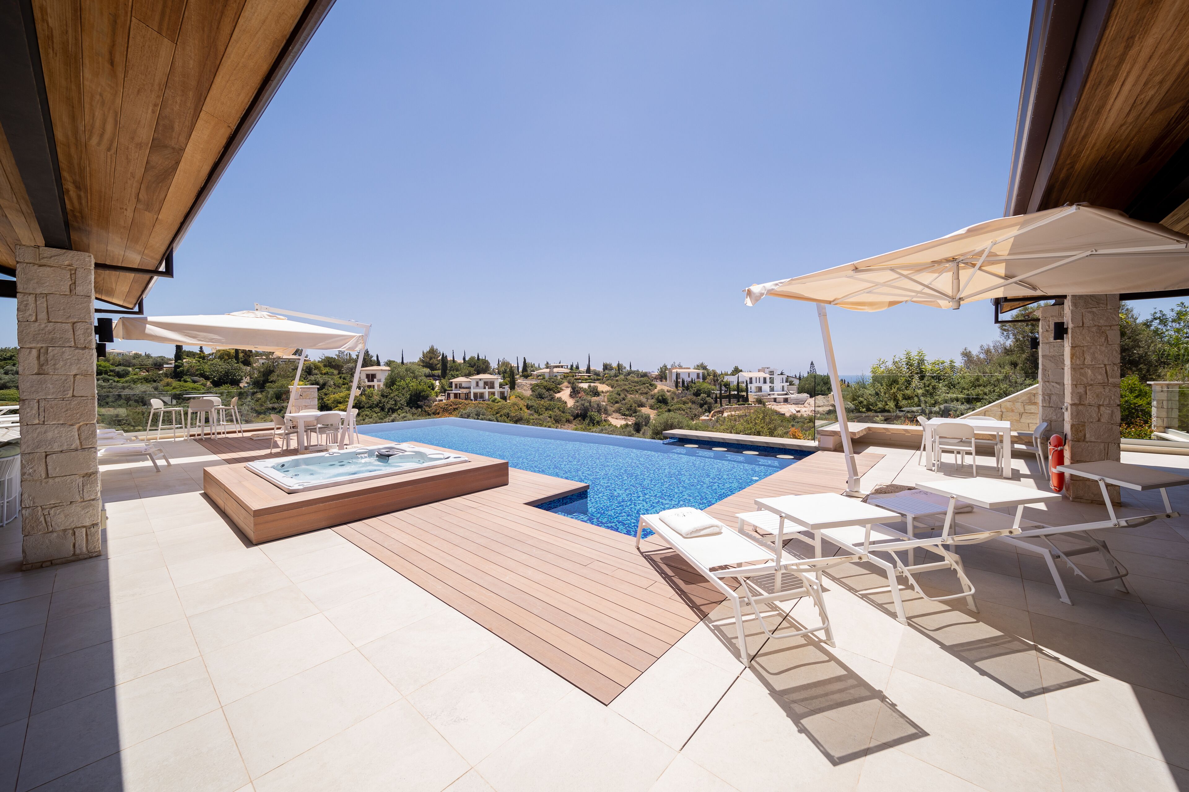 A rooftop pool area with a hot tub, sun loungers, and umbrellas.