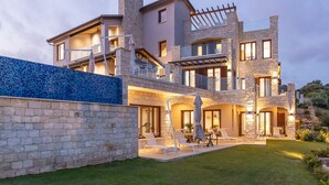A multi-story stone house with a spacious outdoor patio, a swimming pool, and a well-maintained lawn. - Villa Elea, New Deluxe Golf Villa in Aphrodite Hills - 6 Bedrooms, 7 Bathrooms.  (Kouklia)