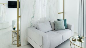A modern living room with a marble partition, a grey sofa, and a gold-framed coffee table.