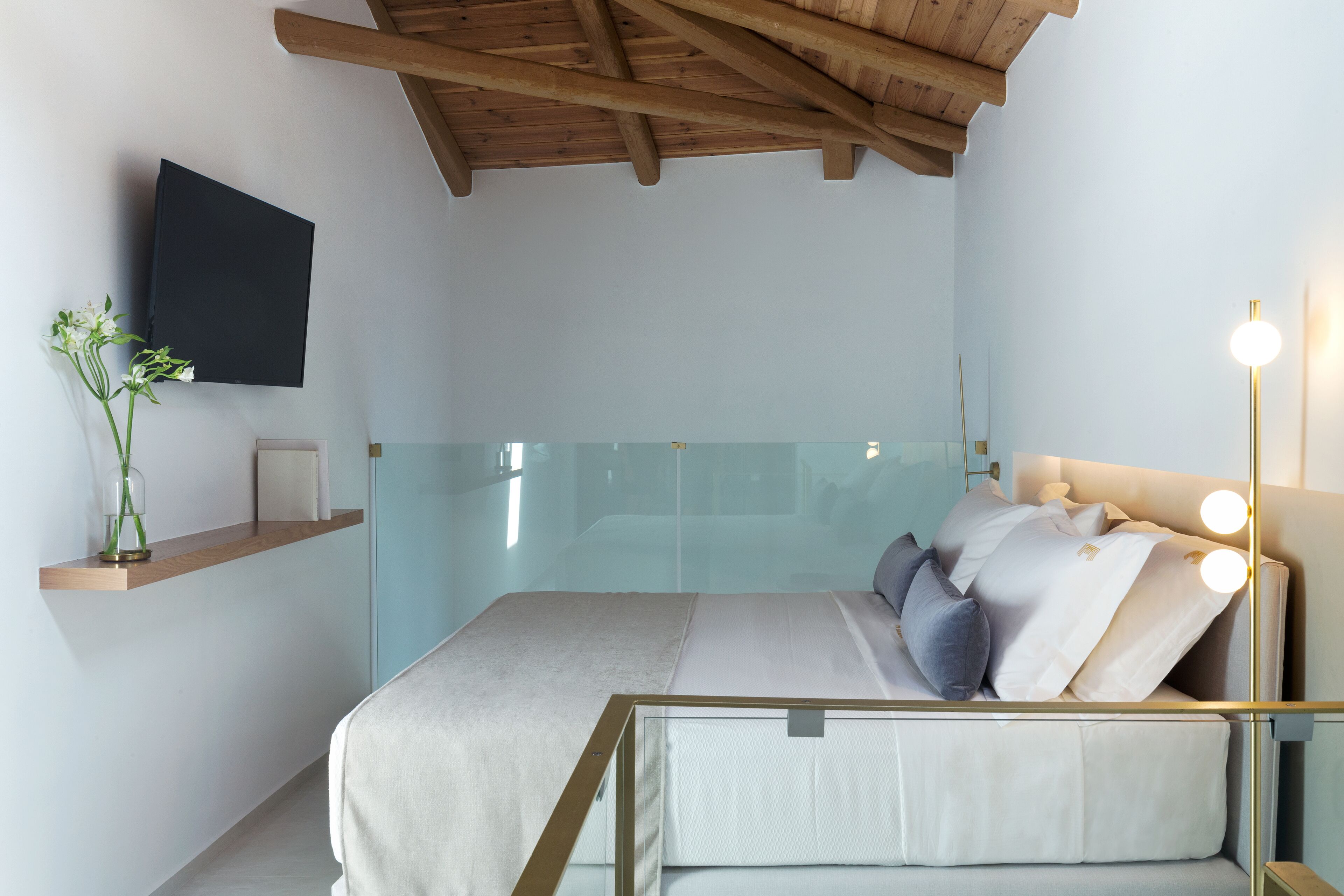 Une chambre à coucher moderne avec un lit, une table de chevet et un téléviseur fixé au mur.