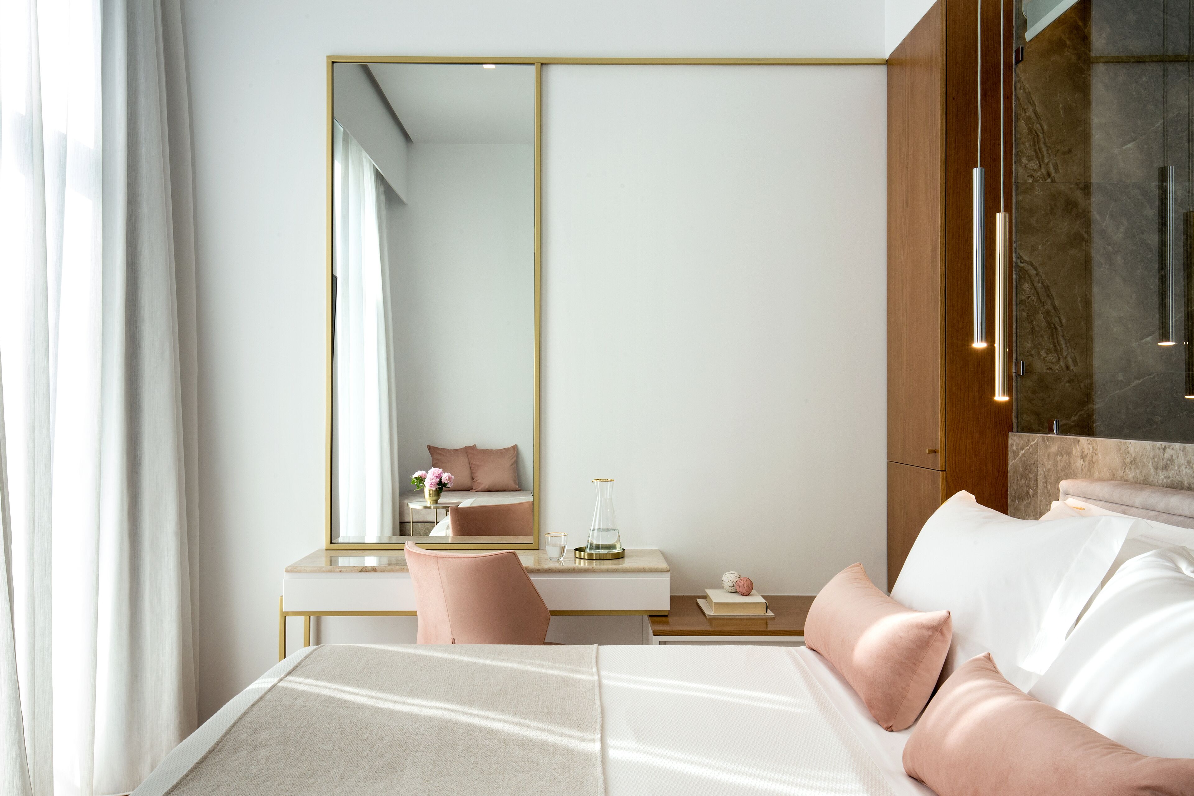 A modern hotel room with a large bed, a bedside table, a mirror, and a view of the bathroom.