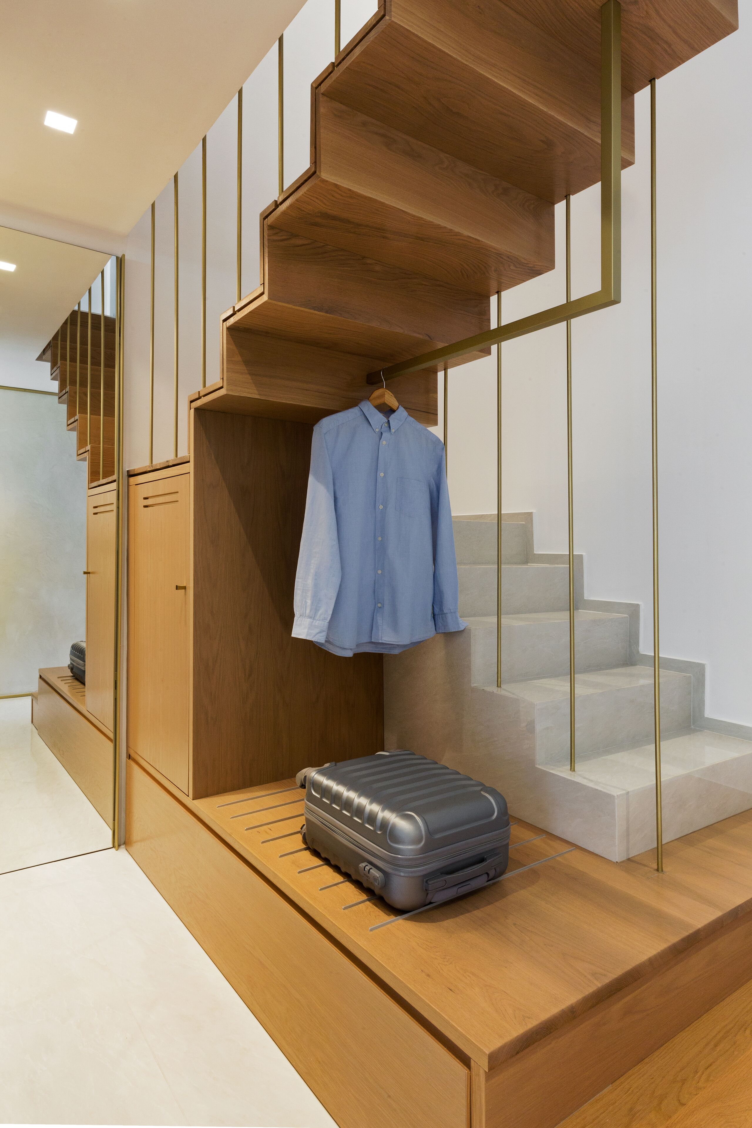 A modern staircase with wooden steps and a hanging garment rack.