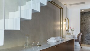 A modern bathroom with a marble countertop, a large mirror, and a marble wall.