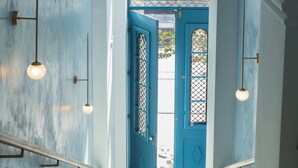 A staircase leading to a blue door with a metal gate, white walls, and hanging pendant lights.