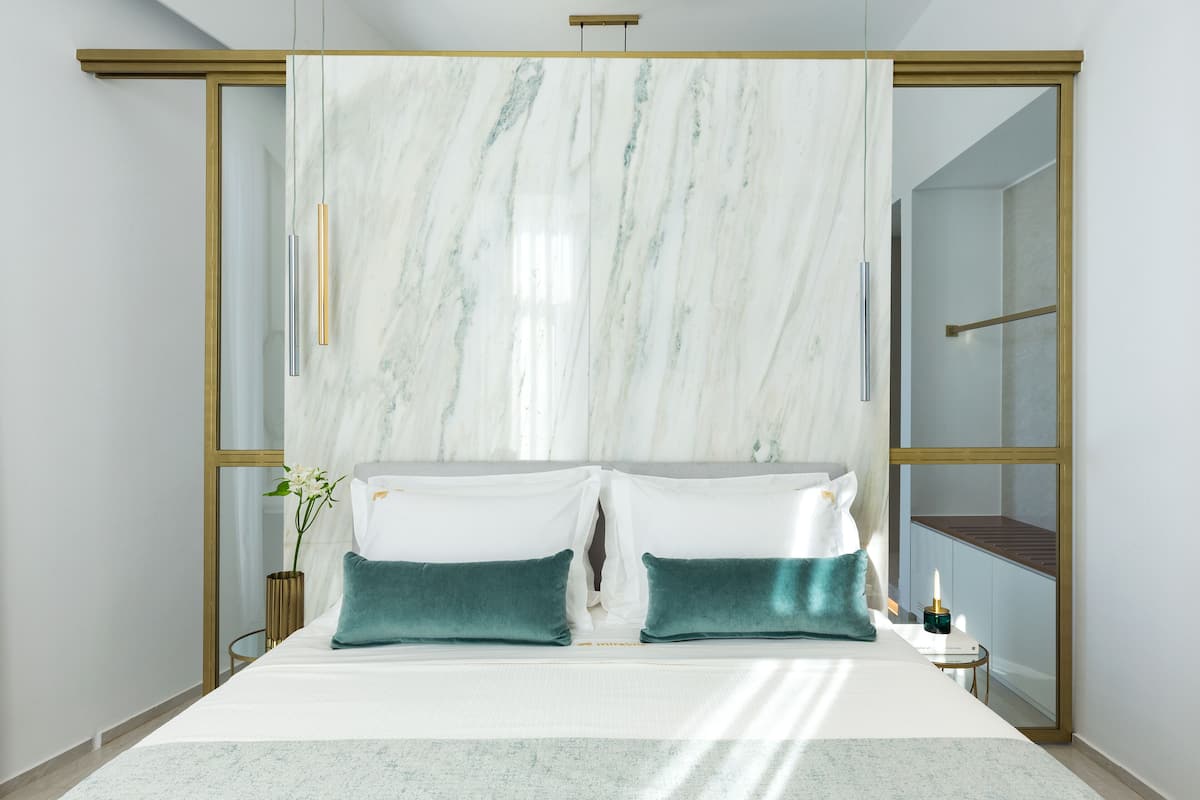 A modern bedroom with a large bed, a marble headboard, and a small bedside table with a candle.