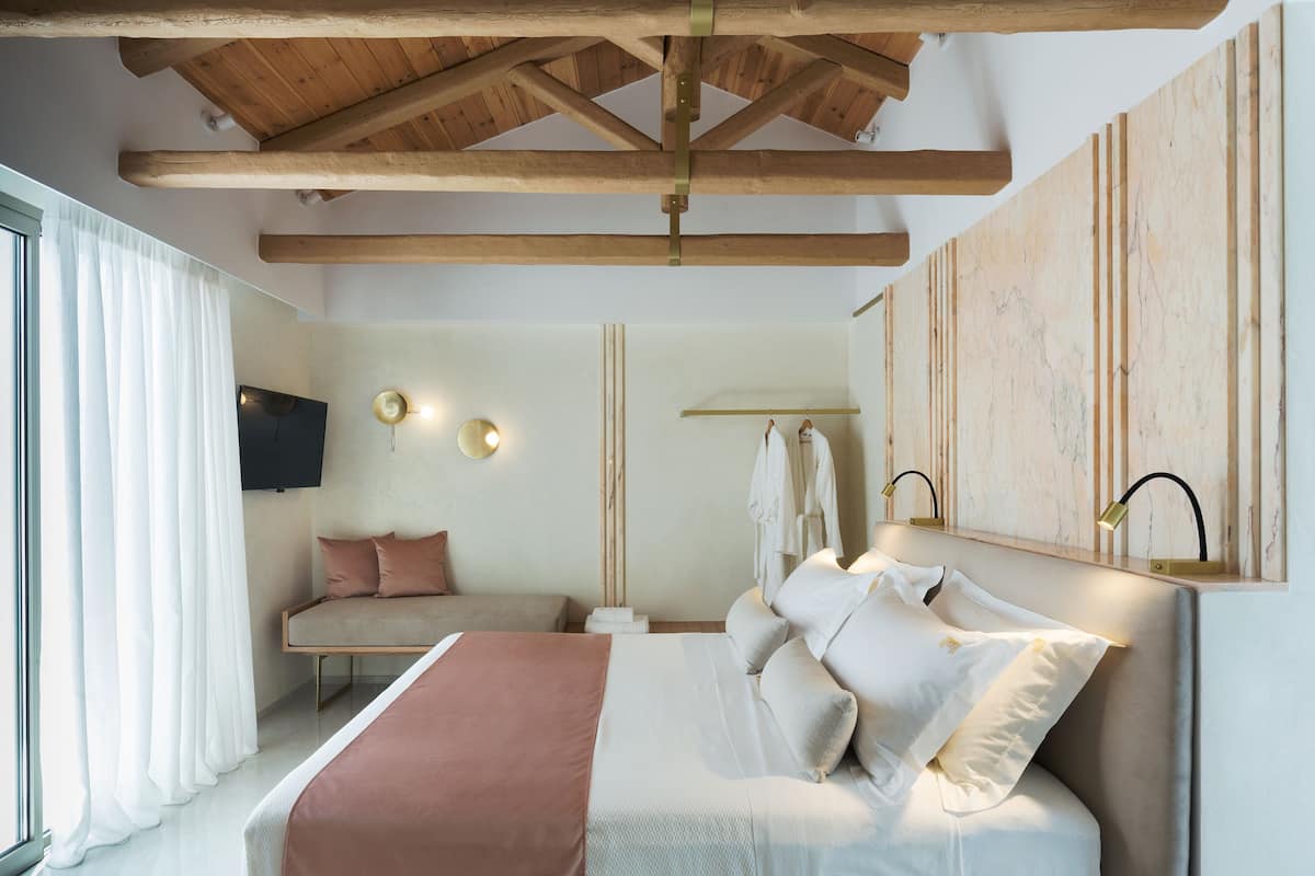A modern bedroom with a wooden ceiling, a bed with white and pink bedding, a TV, and a wall-mounted light fixture.