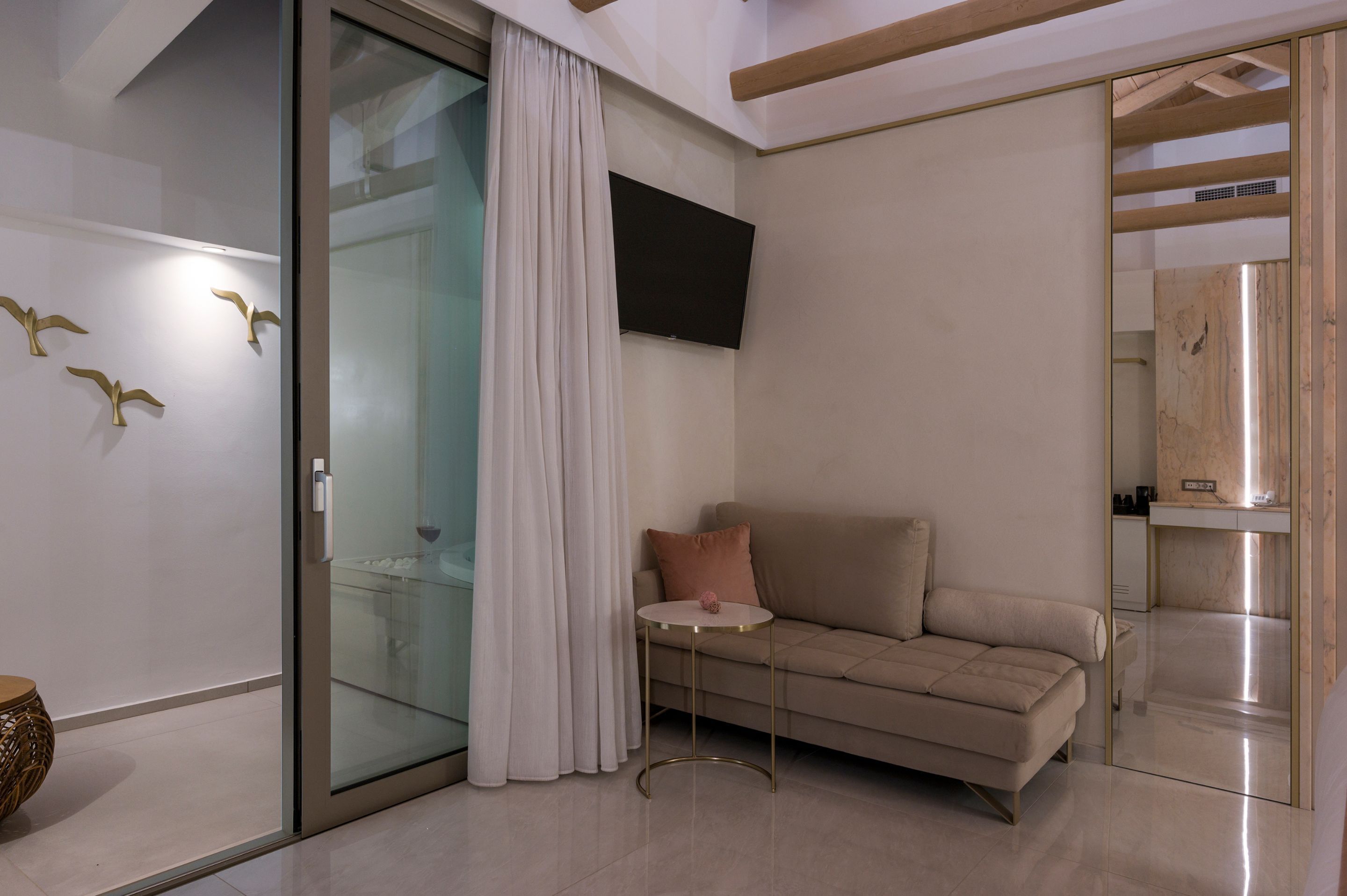 A modern living room with a sofa, a small round table, and a glass partition.