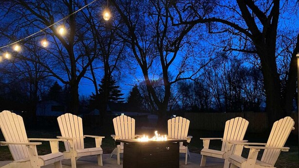 Un patio con sillas Adirondack y un brasero.