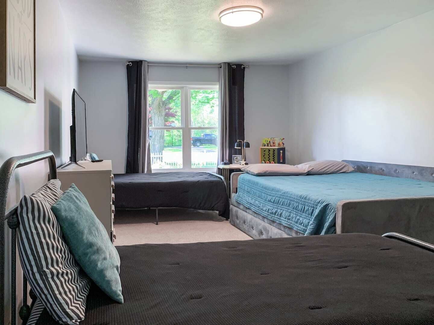 Een slaapkamer met twee bedden, een bureau, een stoel en een raam met gordijnen.
