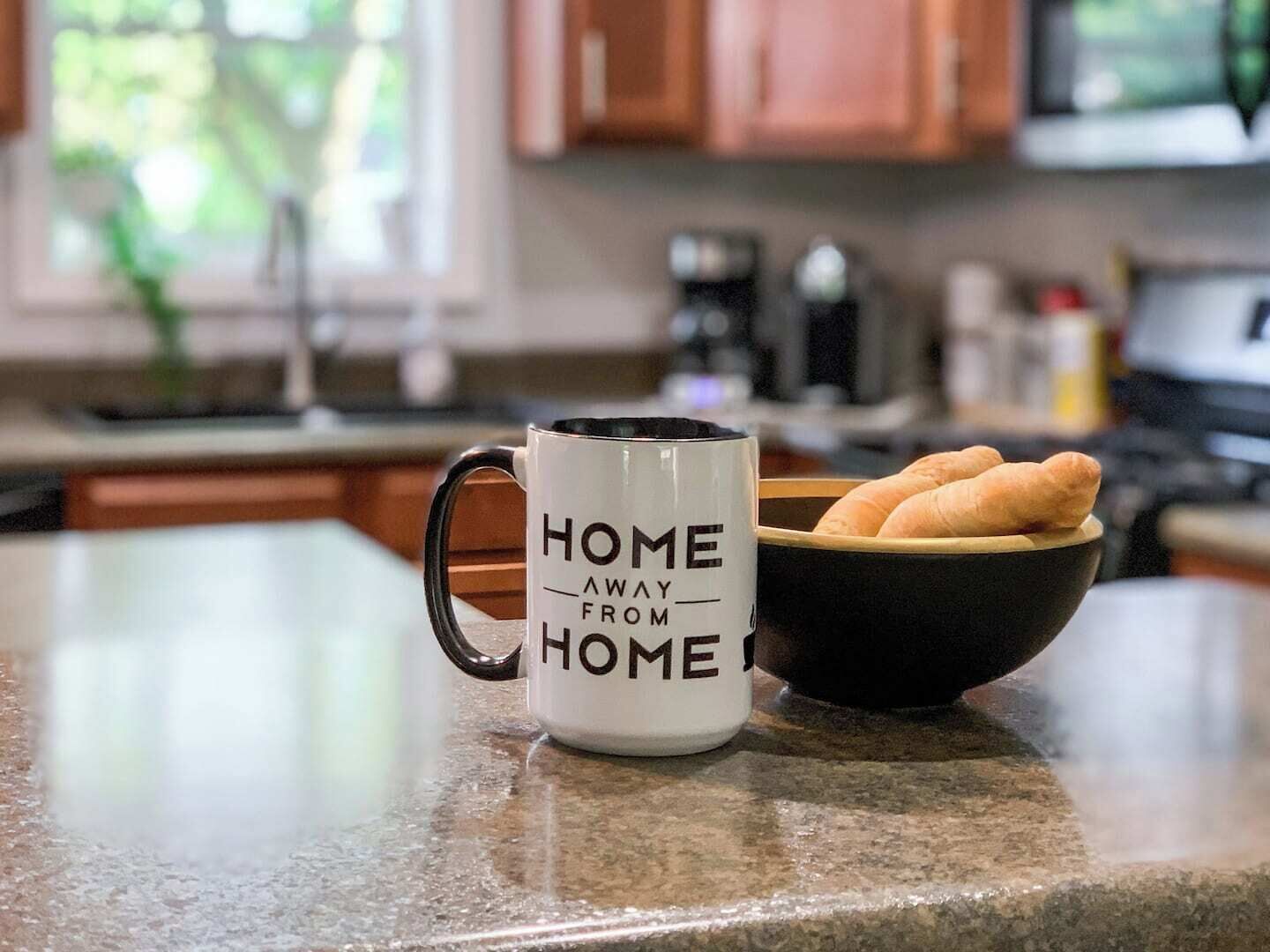Un comptoir de cuisine avec une tasse blanche sur laquelle est inscrit « UN PETIT COIN DE PARADIS » et un bol de pain.