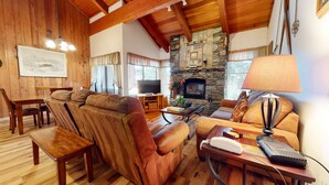 Una sala de estar acogedora con muebles de madera, una chimenea de piedra y un televisor.