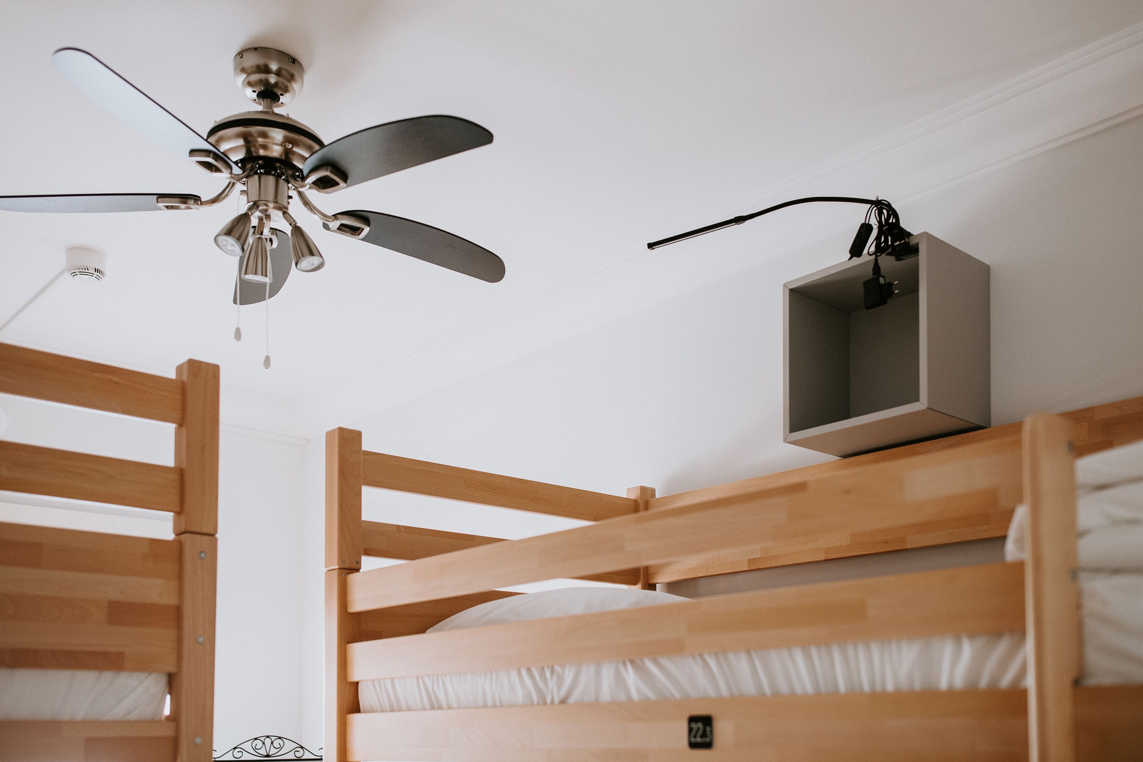 Habitación con literas, ventilador de techo, mesita de noche y toma de corriente.