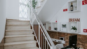 A staircase with white railings leading to a room with a desk, shelves, and a sign that reads "DREAM". - Dream House Hostel (Faro)