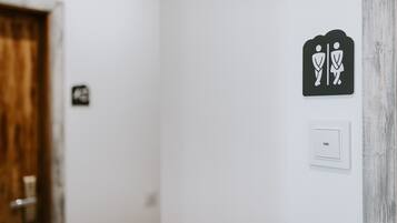 Un letrero de baño con símbolo de hombre y mujer, una puerta y un interruptor de luz en la pared.