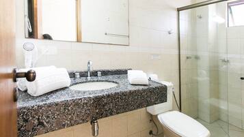 Une salle de bain avec un lavabo sur un plan de travail en granit, des toilettes, une douche à parois de verre et un miroir au-dessus du lavabo.