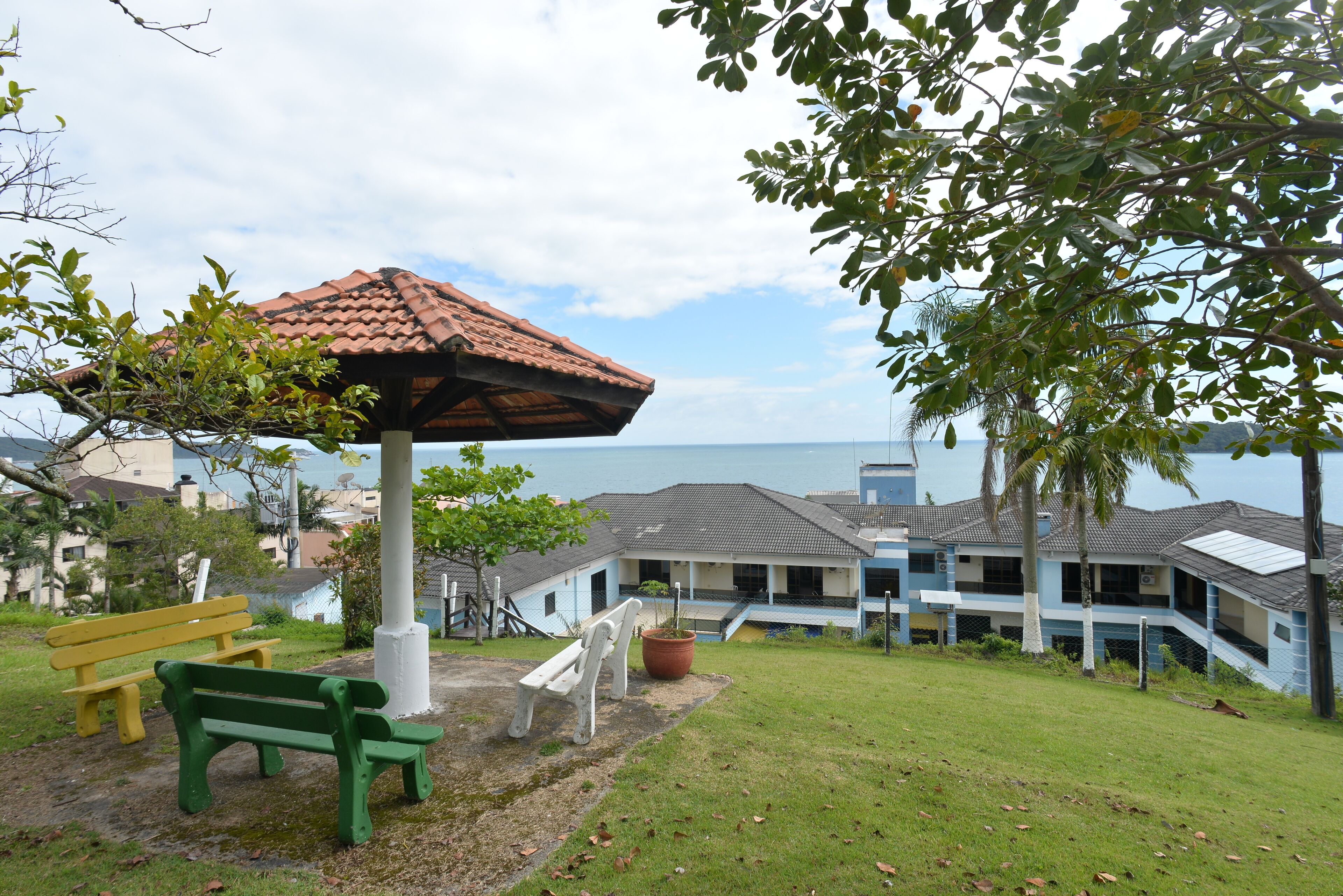 Um parque com um coreto, bancos e vista para o mar.