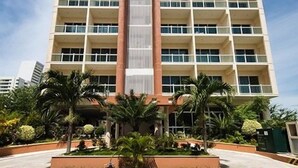 A multi-story hotel with a central atrium, balconies on each floor, and a landscaped area with palm trees. - Hotel RRU Diamante (Acapulco)