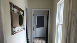 A hallway with a wooden table, a rug, and a mirror on the wall. - Guest suite in the woods with private entry  (Lincoln)