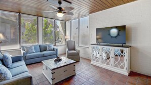 A living room with a sofa, armchair, coffee table, TV, and cabinet. - Beach Access! Heated Community Pool! Float in the pool while looking at the beac (Port Aransas)