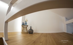 Experience the modern aesthetic of this stylish room, featuring a curved architectural feature and a cozy side table with a beautiful orchid.