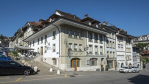 Un hôtel à plusieurs étages, de style architectural européen classique, qui se distingue par une entrée imposante avec une porte en bois et de nombreuses fenêtres.