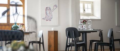 A modern dining area with a wooden table, black chairs, and a large window providing natural light.