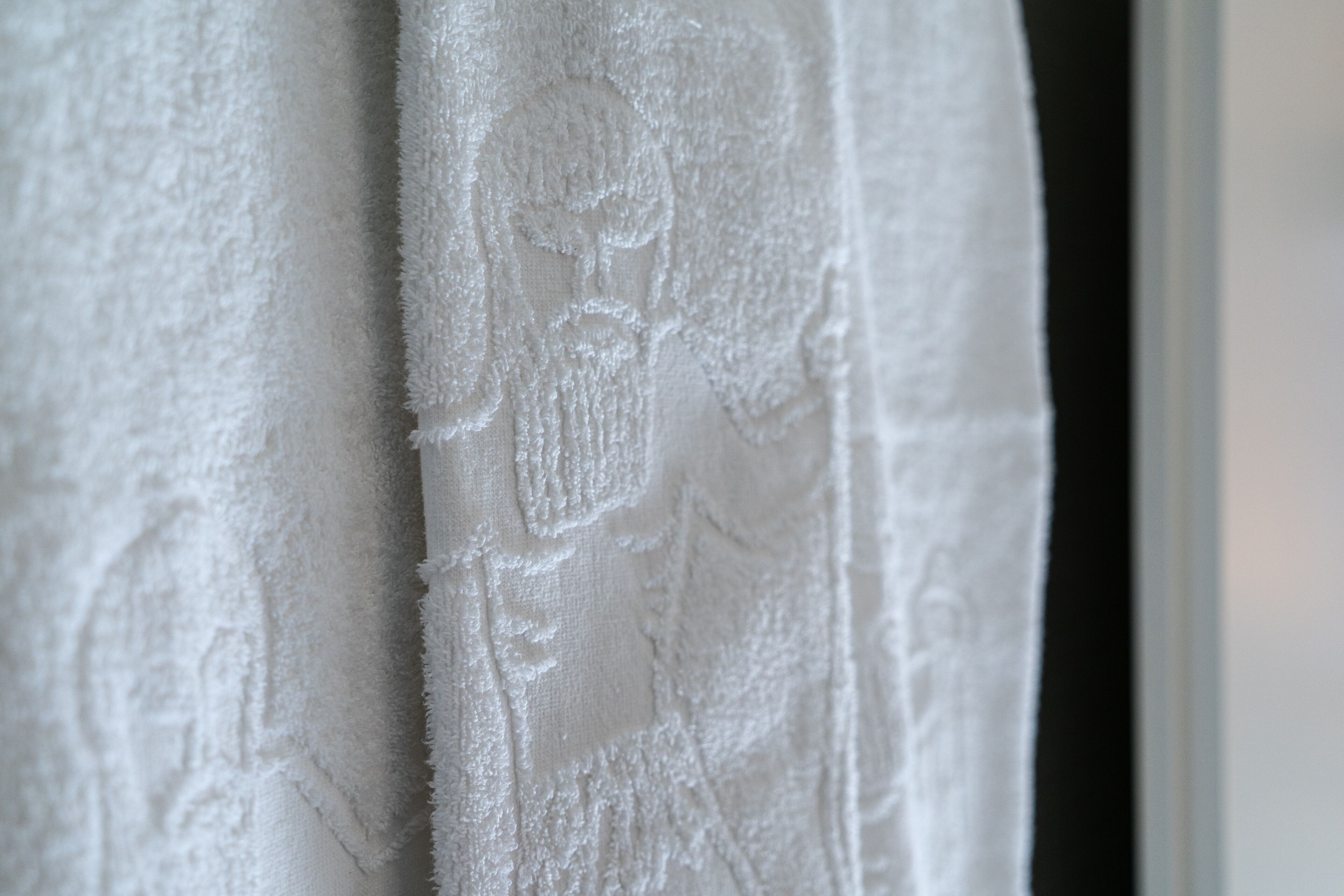 A close-up of a white textured fabric with a floral pattern.