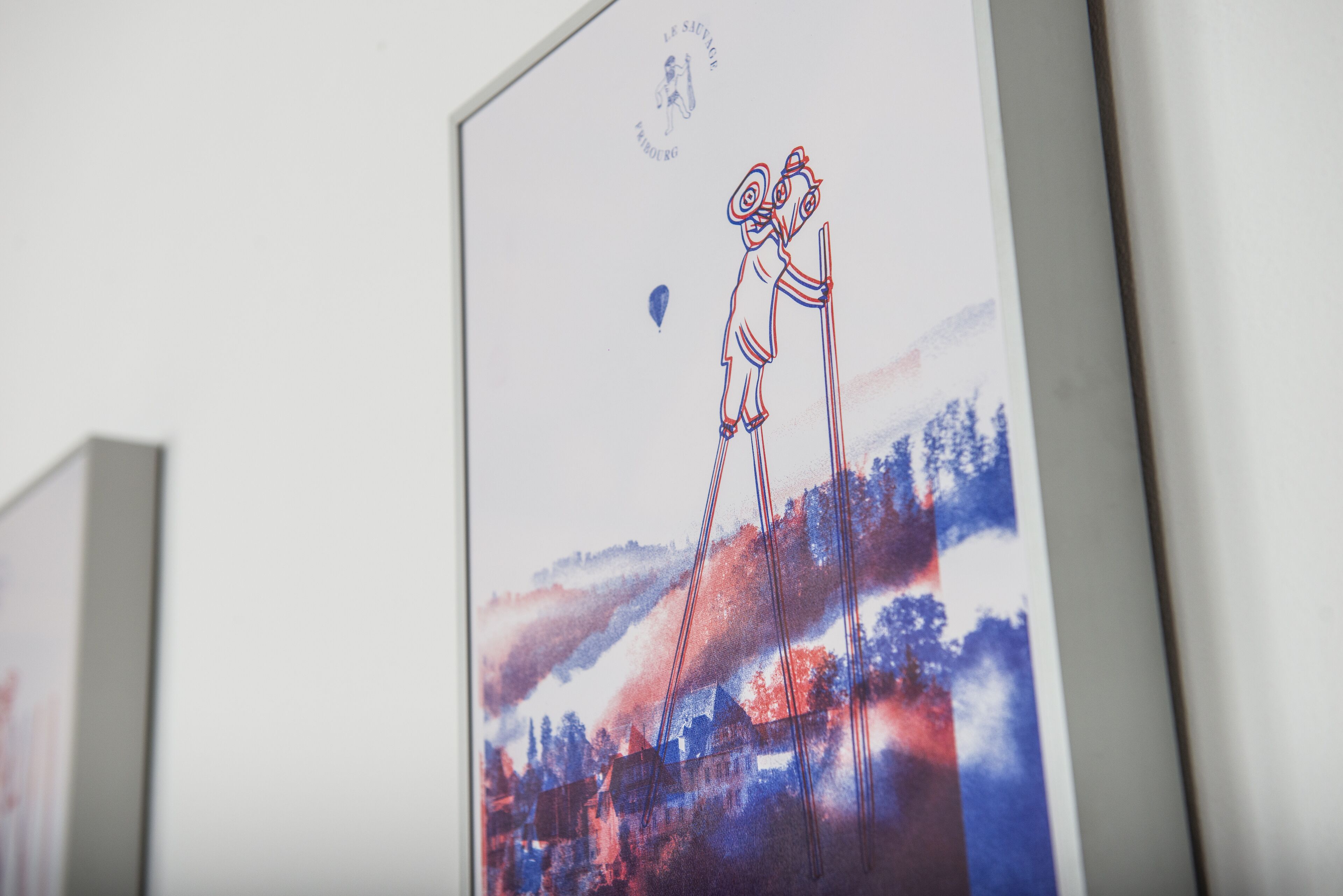 Une œuvre d’art encadrée, représentant des figures abstraites et un paysage.