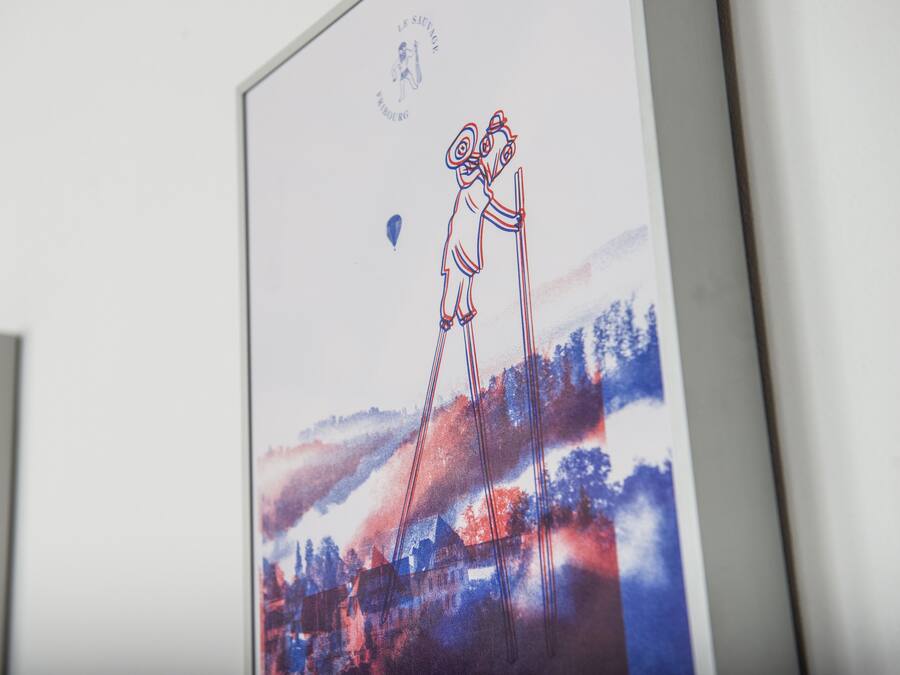 Une œuvre d’art encadrée, représentant des figures abstraites et un paysage.