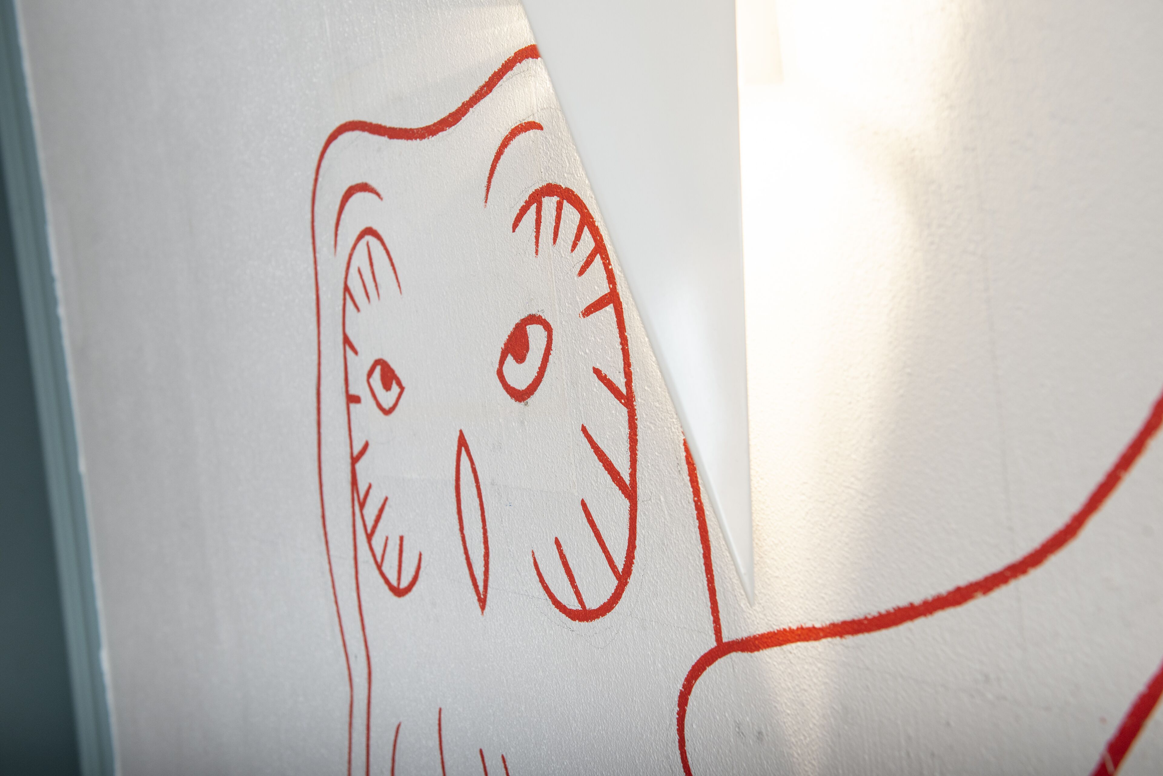 A whiteboard with a red outline drawing of a cat's face.