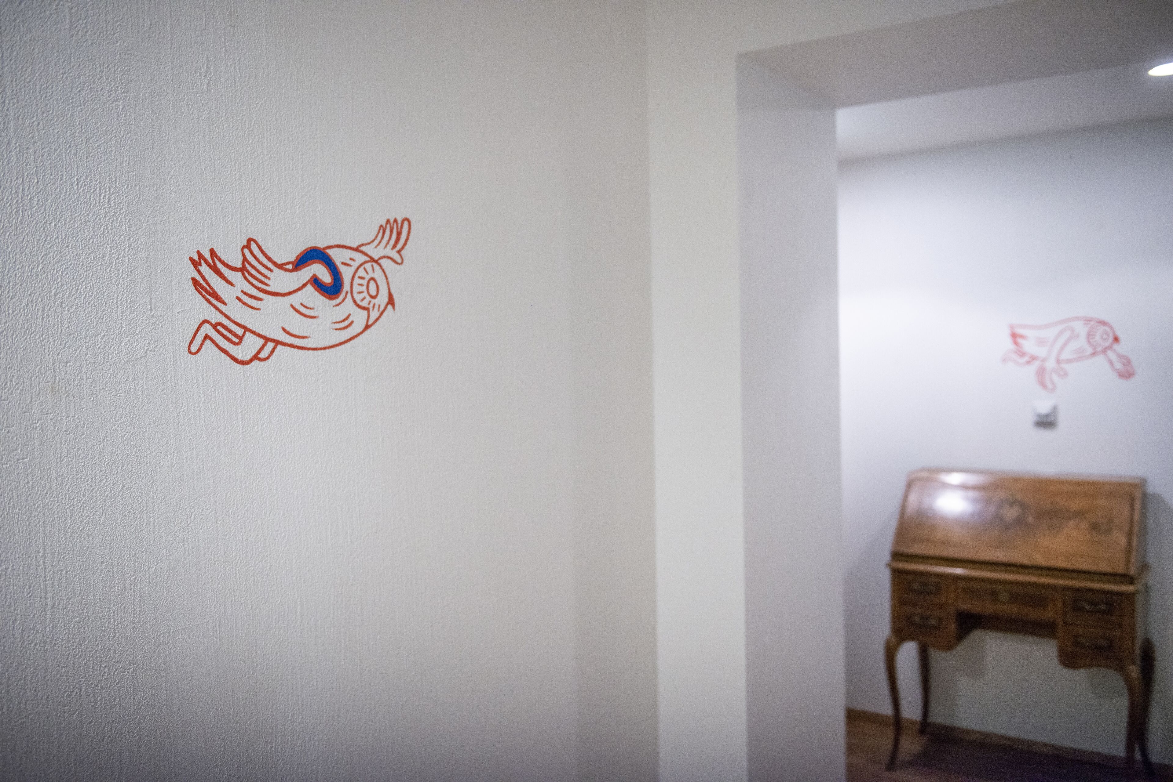 A room with a wooden piano and two wall drawings.
