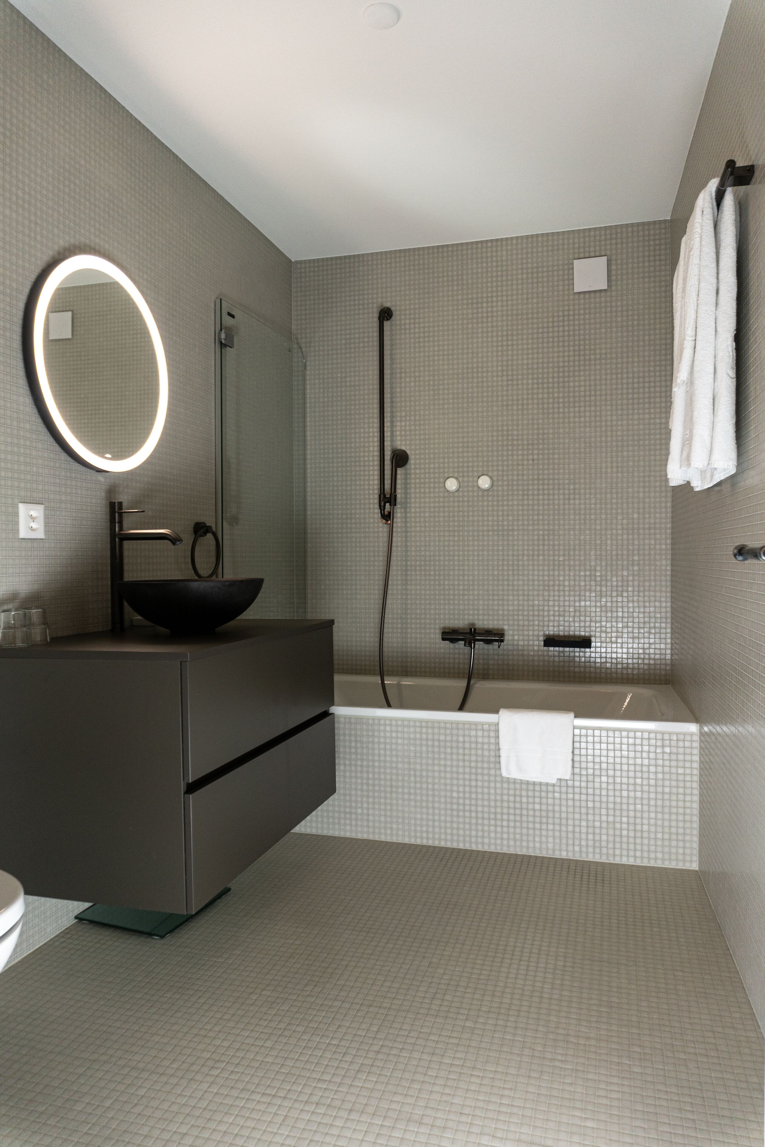 Une salle de bain moderne avec un grand miroir, un lavabo noir sur pied, une douche et une baignoire.