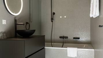 Une salle de bain moderne avec un grand miroir, un lavabo noir sur pied, une douche et une baignoire.