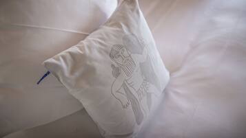 Ein Kopfkissen mit einem monochromen Stickdesign auf einem Bett.