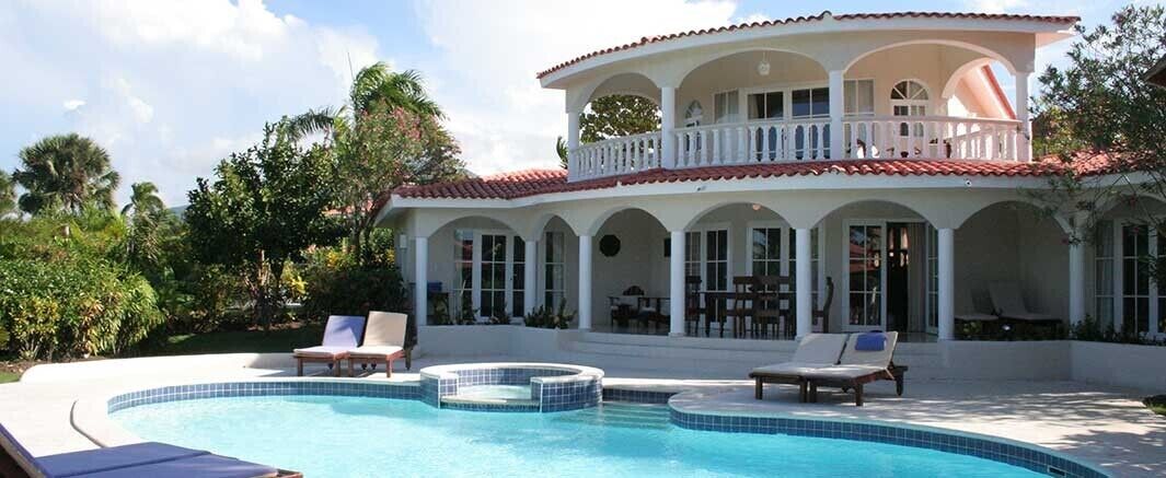 A two-story house with a swimming pool, outdoor seating, and a balcony.