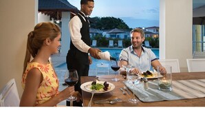 A dining table with a view of a pool and buildings in the background. - Happy As A Clam (Puerto Plata)