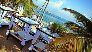 A beachside lounge area with white canopies, lounge chairs, and a view of the ocean. - Happy As A Clam (Puerto Plata)