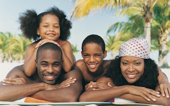 A family of four on a beach with palm trees in the background. - Happy As A Clam (Puerto Plata)