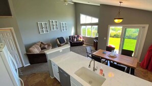 A kitchen with a white countertop, a sink, and a dining area with a table and chairs. - Golf Course Condo w/ Loft on Bayside at Lake Mac! (Brule)
