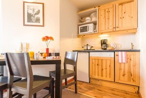 A compact kitchen with wooden cabinets, a microwave, a coffee maker, and a dishwasher.