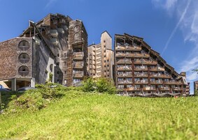 Un edificio de varios pisos con un diseño arquitectónico único, con balcones y una combinación de texturas de ladrillo y madera.