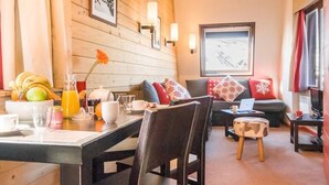 Una sala acogedora con comedor, paredes de madera y un sofá con cojines rojos.