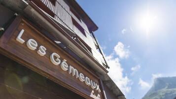 A wooden sign with the text "Les Gémaux" against a clear sky.
