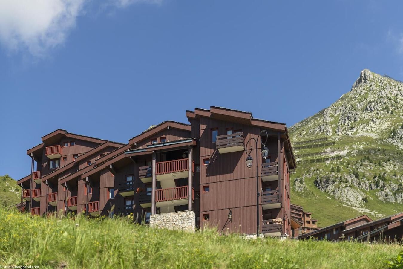 A multi-story wooden building with balconies, set against a mountainous backdrop.