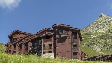 A multi-story wooden building with balconies, set against a mountainous backdrop.