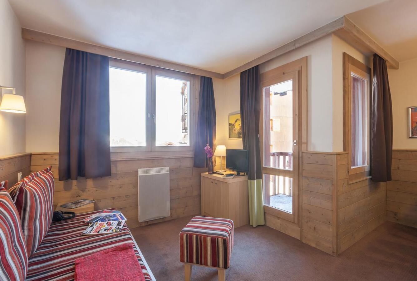 A cozy room with a bed, a small table with a lamp, and a window with curtains.