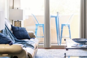 A living room with a sofa, a coffee table, and a view of the outside through a sliding glass door. - Old Town Scottsdale|Stylish New Condo| Heated Pool (Scottsdale)