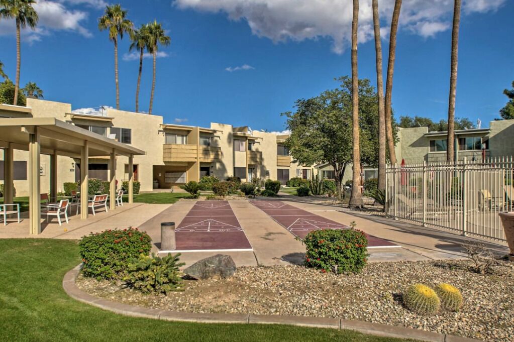 A residential building with multiple floors, outdoor seating, and a courtyard with palm trees.