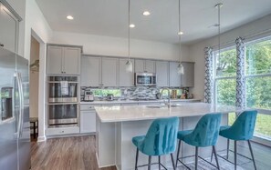 A modern kitchen with a large island, stainless steel appliances, and pendant lighting. - Modern 5 Bedroom 4 Full Bath Bethany Beach Home (Ocean View)