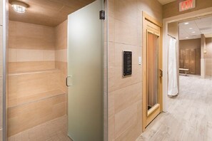 A hotel corridor with a wooden door, a wall-mounted sign, and a shower area.